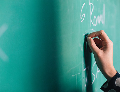 Close up of a person writing on a chalkboard